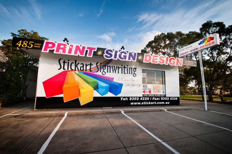 The Stickart Signwriting shop on Barry Road, Dallas — roof letters, rainbow arrow mural and pylon sign.